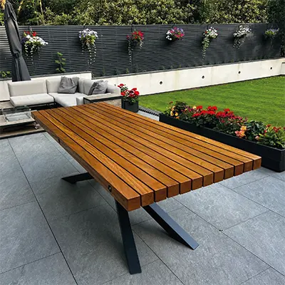 An outdoor garden table made with Timbersource's West African Iroko strips for the table top in a contemporary garden