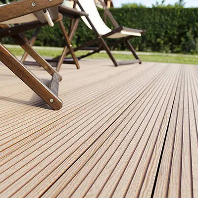 A close up of a Yellow Balau Deck with several deck chairs on in a garden