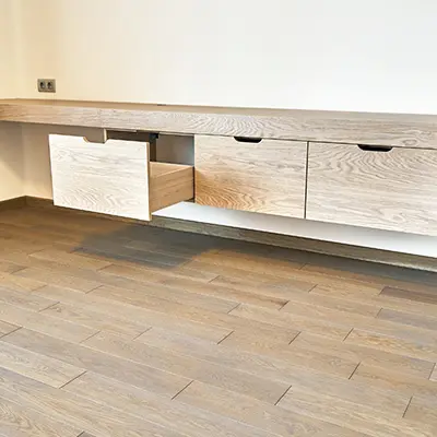 A room with Oak flooring, and a shelving unit attached to the wall