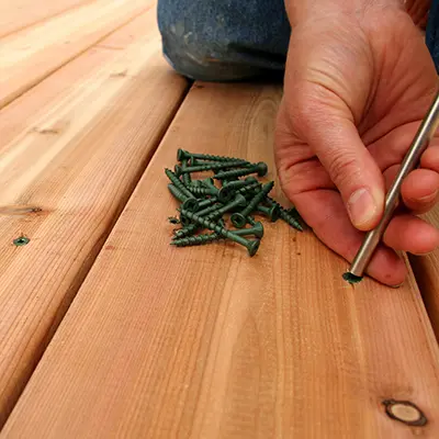 Timbersource's Canadian Western Red Cedar being laid as decking with a close up of a person screwing it down with green screws