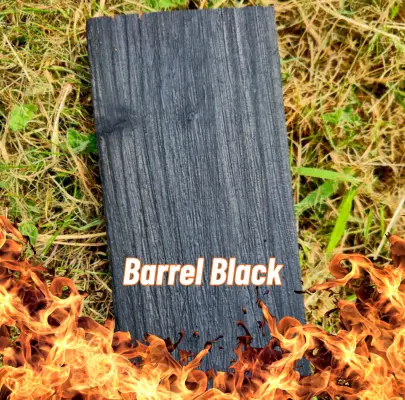 A piece of Charred (Barrel Black) Larch sitting on some grass with flames at the bottom